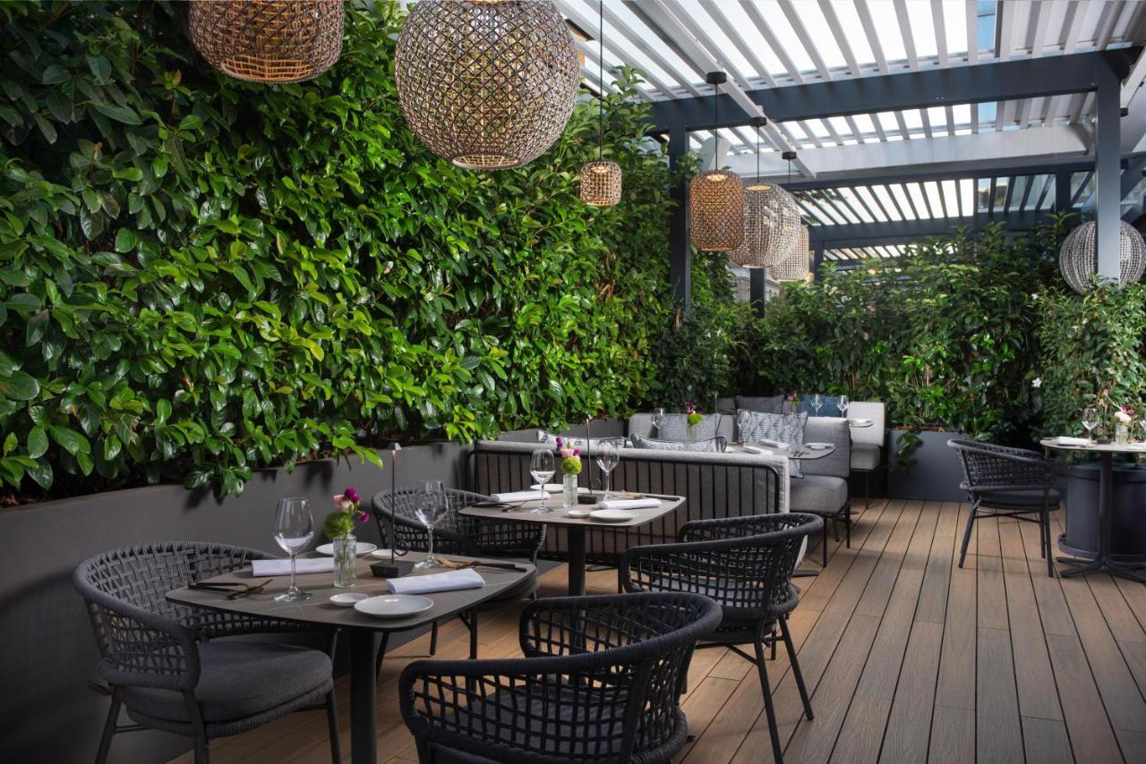 een restaurant met tafels, stoelen en planten bij NH Collection Roma Centro in Rome