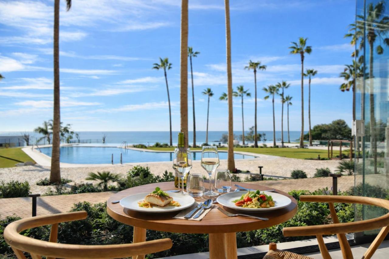 een tafel met twee borden eten en uitzicht op de oceaan bij Hotel Punta Bermeja Premium in El Puerto de Santa María +43 
