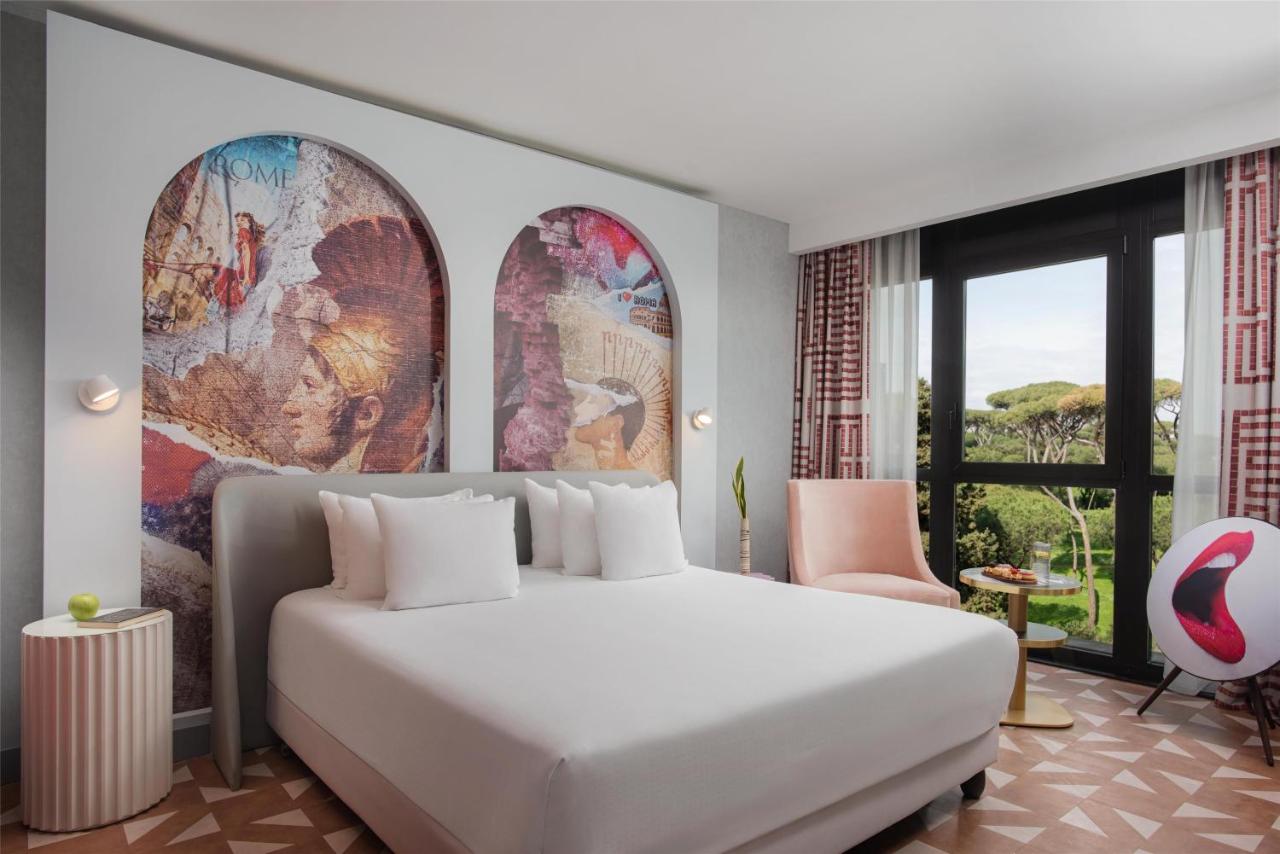 een slaapkamer met een groot wit bed en grote ramen bij nhow Roma Vittorio Veneto in Rome