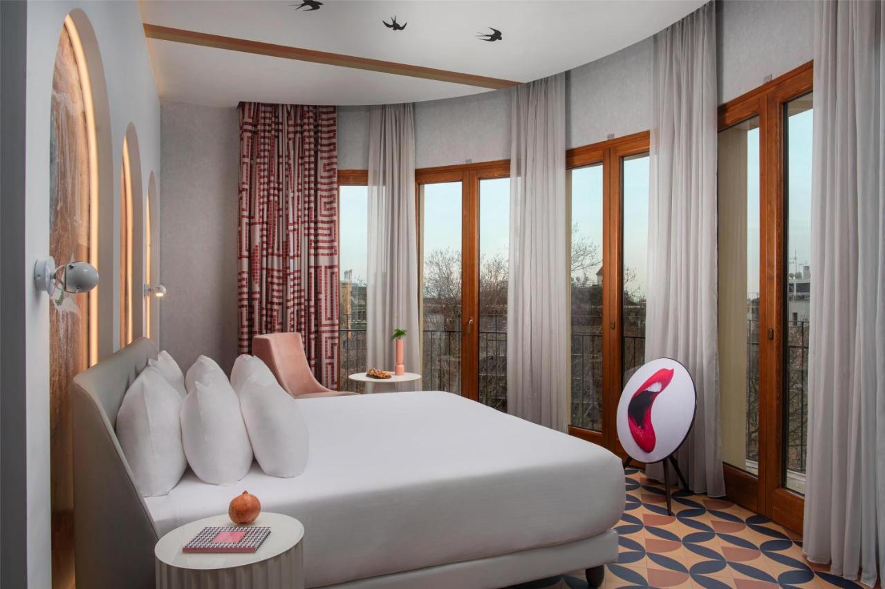 een slaapkamer met een groot wit bed en ramen bij nhow Roma Vittorio Veneto in Rome