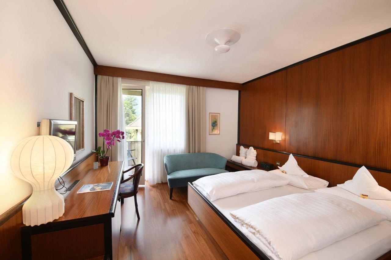 een slaapkamer met een bed, een bureau en een stoel bij Hotel Juliane in Merano