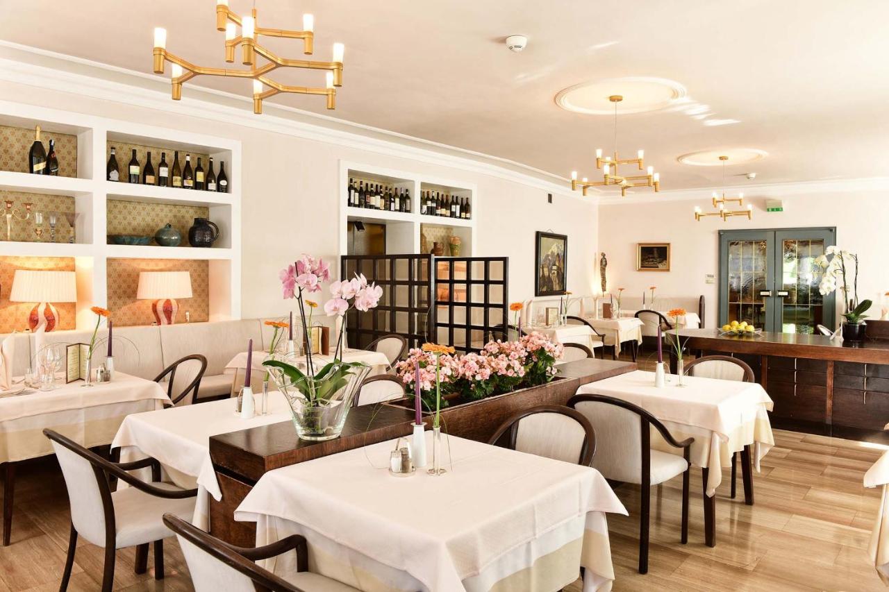 een restaurant met witte tafels en stoelen en bloemen bij Hotel Juliane in Merano