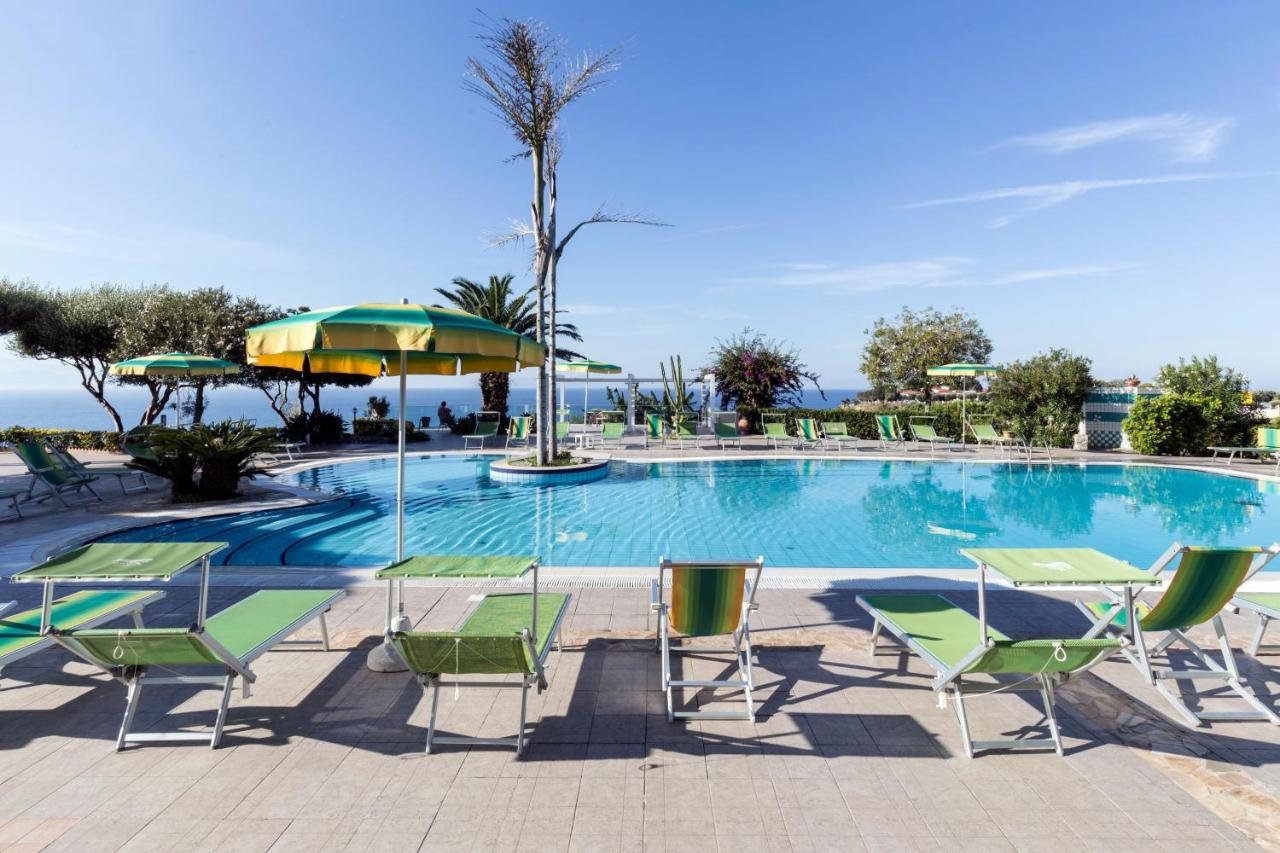 een zwembad met stoelen en parasols aan de oceaan bij Hotel Residence Sciaron in Capo Vaticano
