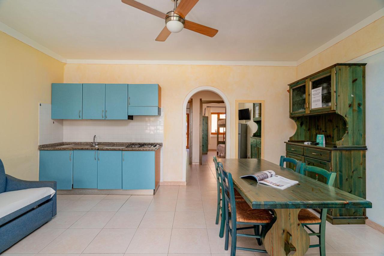 een keuken met blauwe kastjes en een tafel met stoelen bij Club Esse Residence Capo D'orso in Palau
