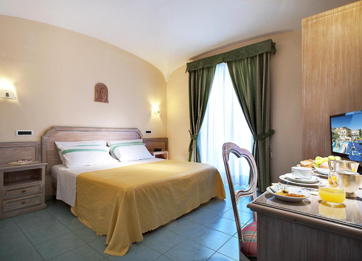 een slaapkamer met een bed en een tafel met een televisie bij Hotel Royal Terme in Ischia Town