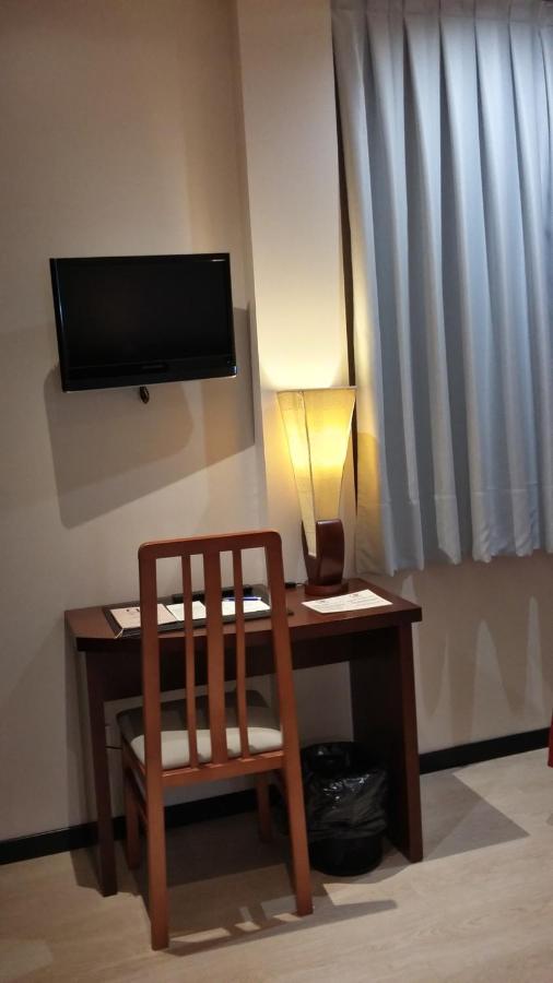 een bureau met een stoel en een televisie aan de muur bij Hotel Don Felipe in Segovia
