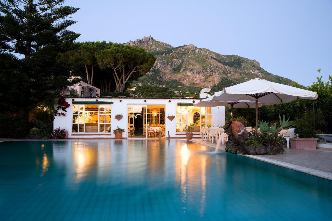 een zwembad met een parasol en een huisje bij Hotel Villa Melodie - Adults Only in Forio d'Ischia