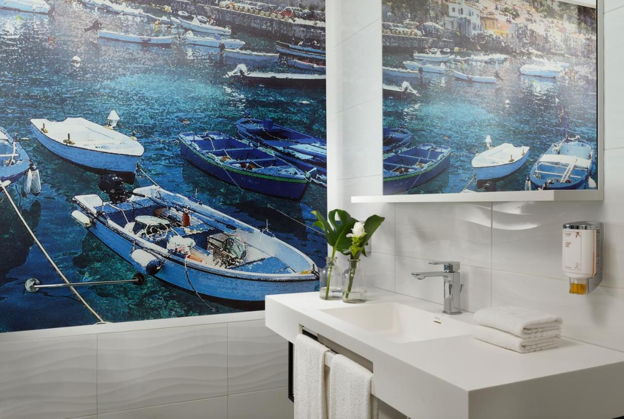 een badkamer met een schilderij van boten op het water bij Falkensteiner Club Funimation Garden Calabria in Curinga