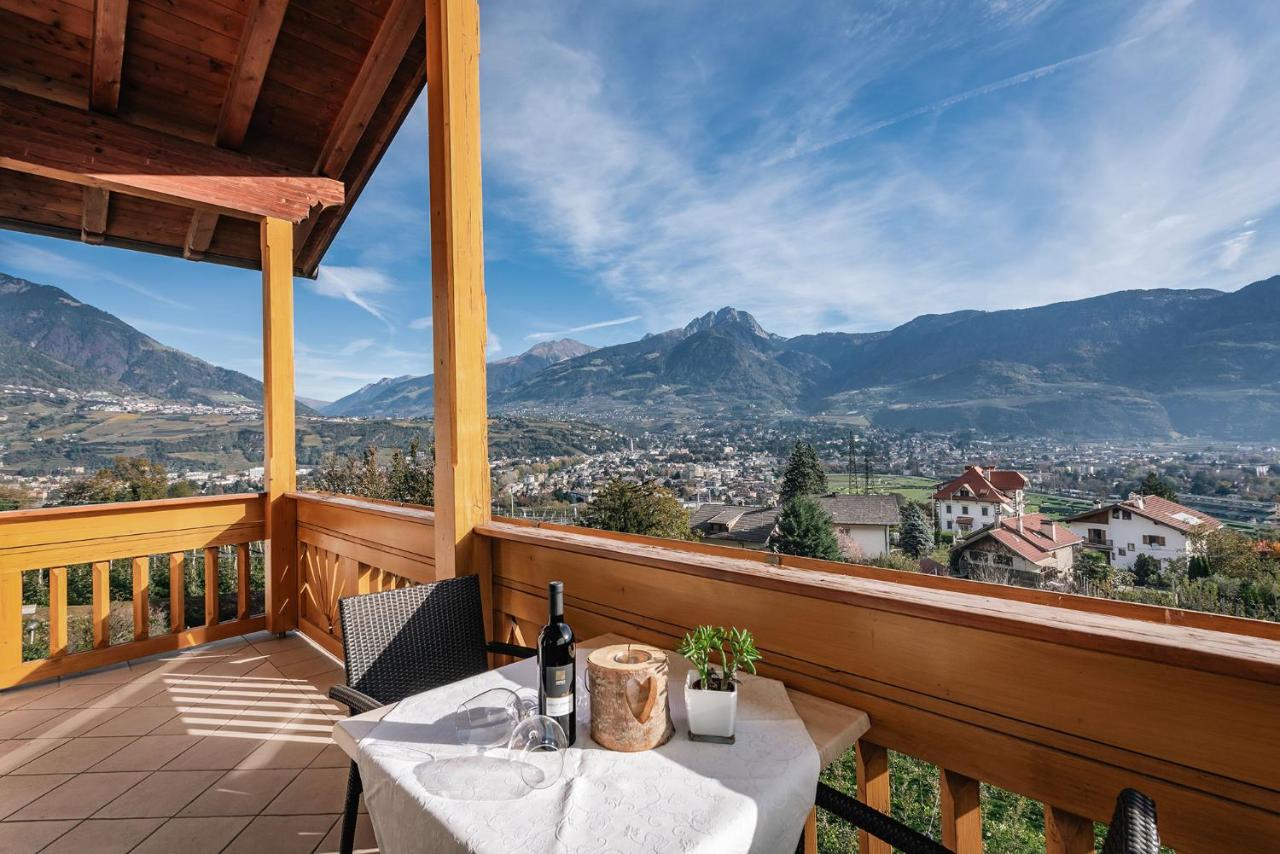 een tafel en stoelen op een balkon met uitzicht op de bergen bij Landhaus Hotel Kristall in Marlengo