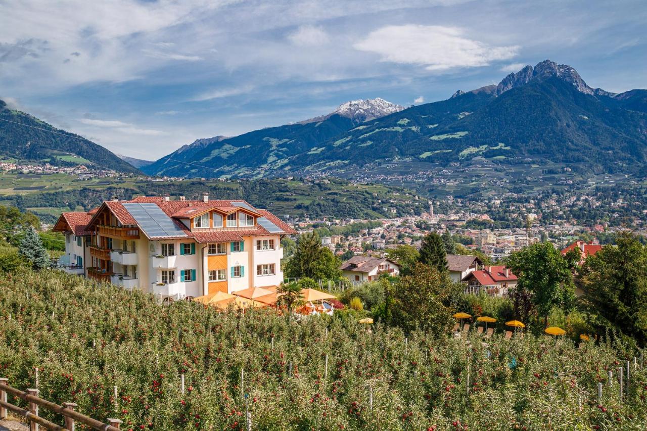 een gebouw op een heuvel met bergen op de achtergrond bij Landhaus Hotel Kristall in Marlengo