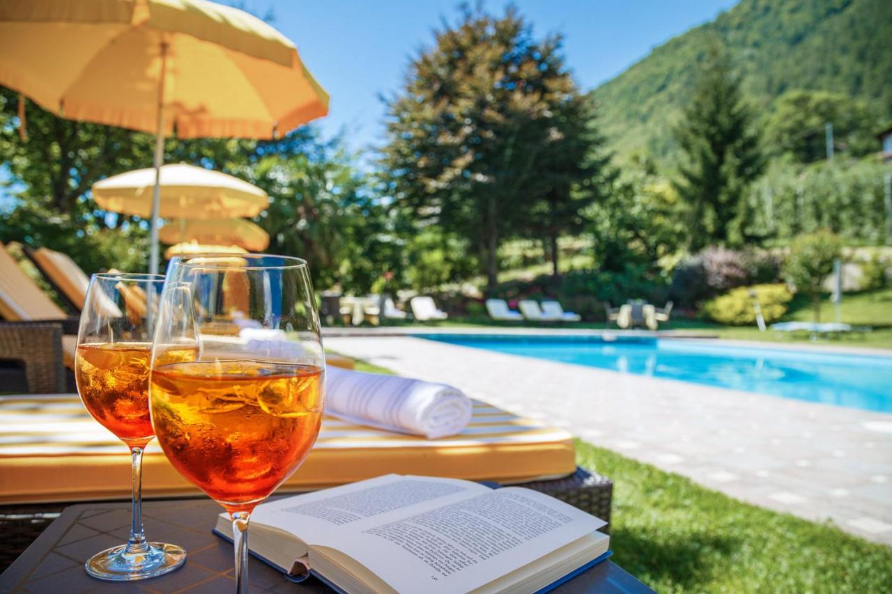 een glas wijn en een boek op een tafeltje naast een zwembad bij Landhaus Hotel Kristall in Marlengo
