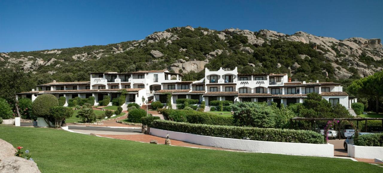 een groot wit gebouw met een berg op de achtergrond bij Hotel La Bisaccia in Baja Sardinia