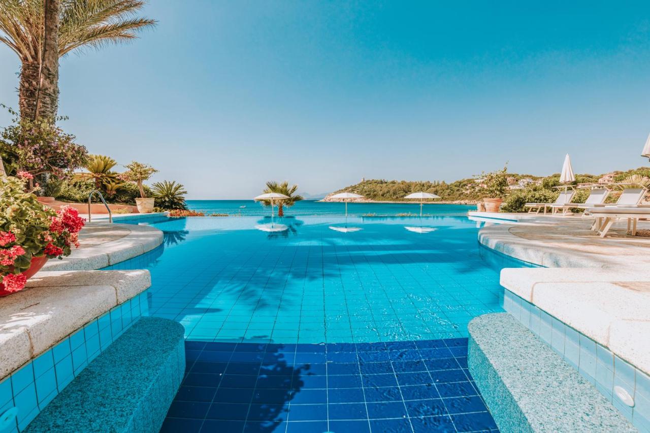 een zwembad met blauw water en palmbomen bij Hotel La Bitta - Bovis Hotels in Àrbatax