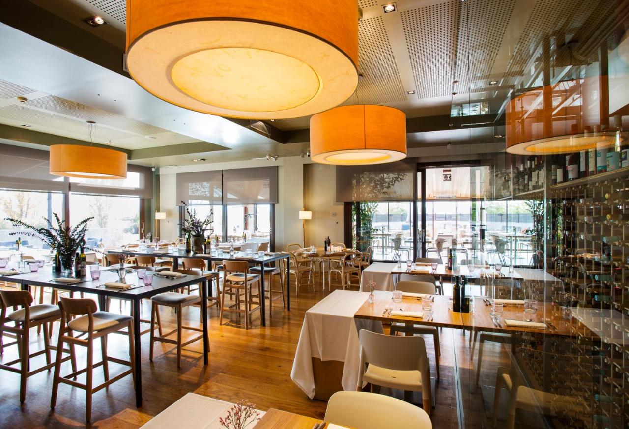 een restaurant met tafels en stoelen en grote ramen bij Qgat Restaurant Events & Hotel in Sant Cugat del Vallès
