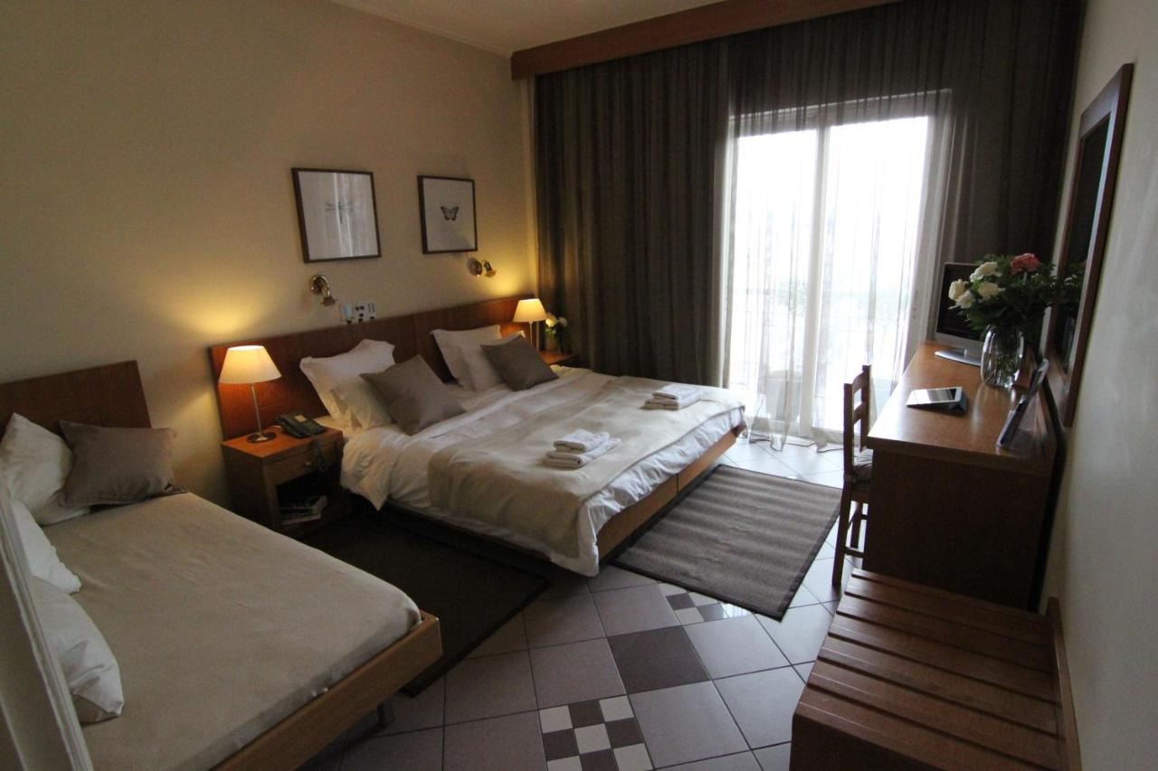 een hotelkamer met twee bedden en een raam bij Achillion Hotel in Athene