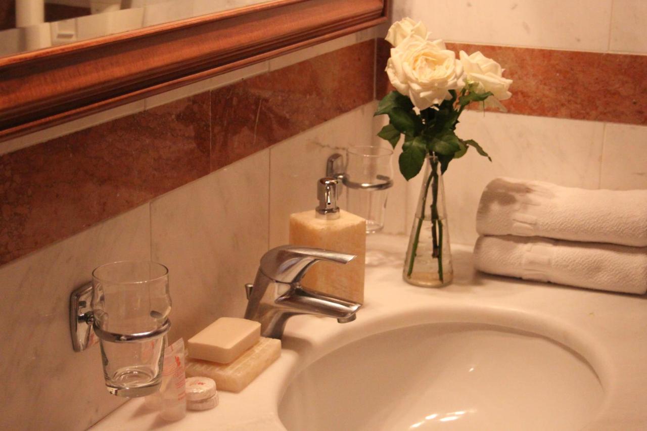 een wastafel in de badkamer met een vaas bloemen erop bij Achillion Hotel in Athene
