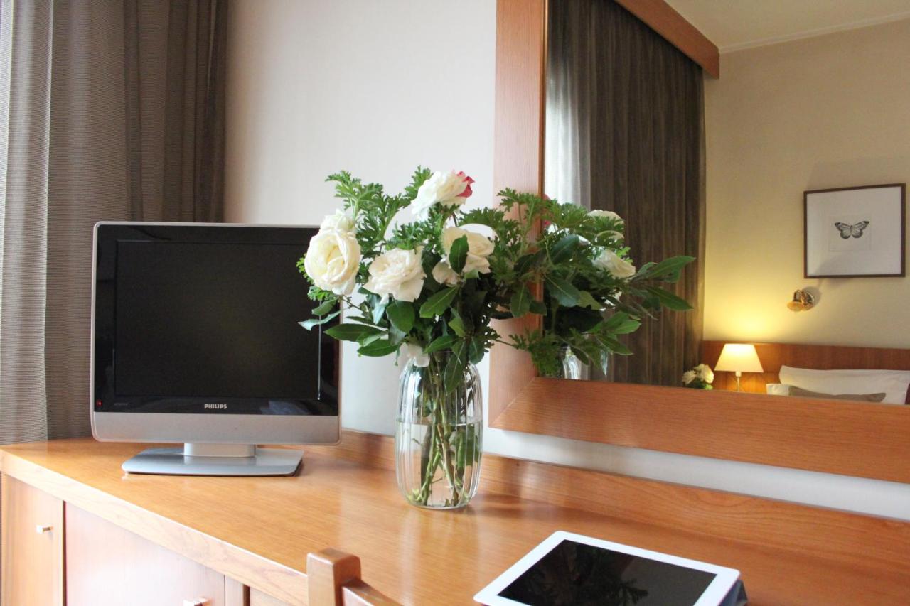een vaas met bloemen op een tafel met een televisie bij Achillion Hotel in Athene
