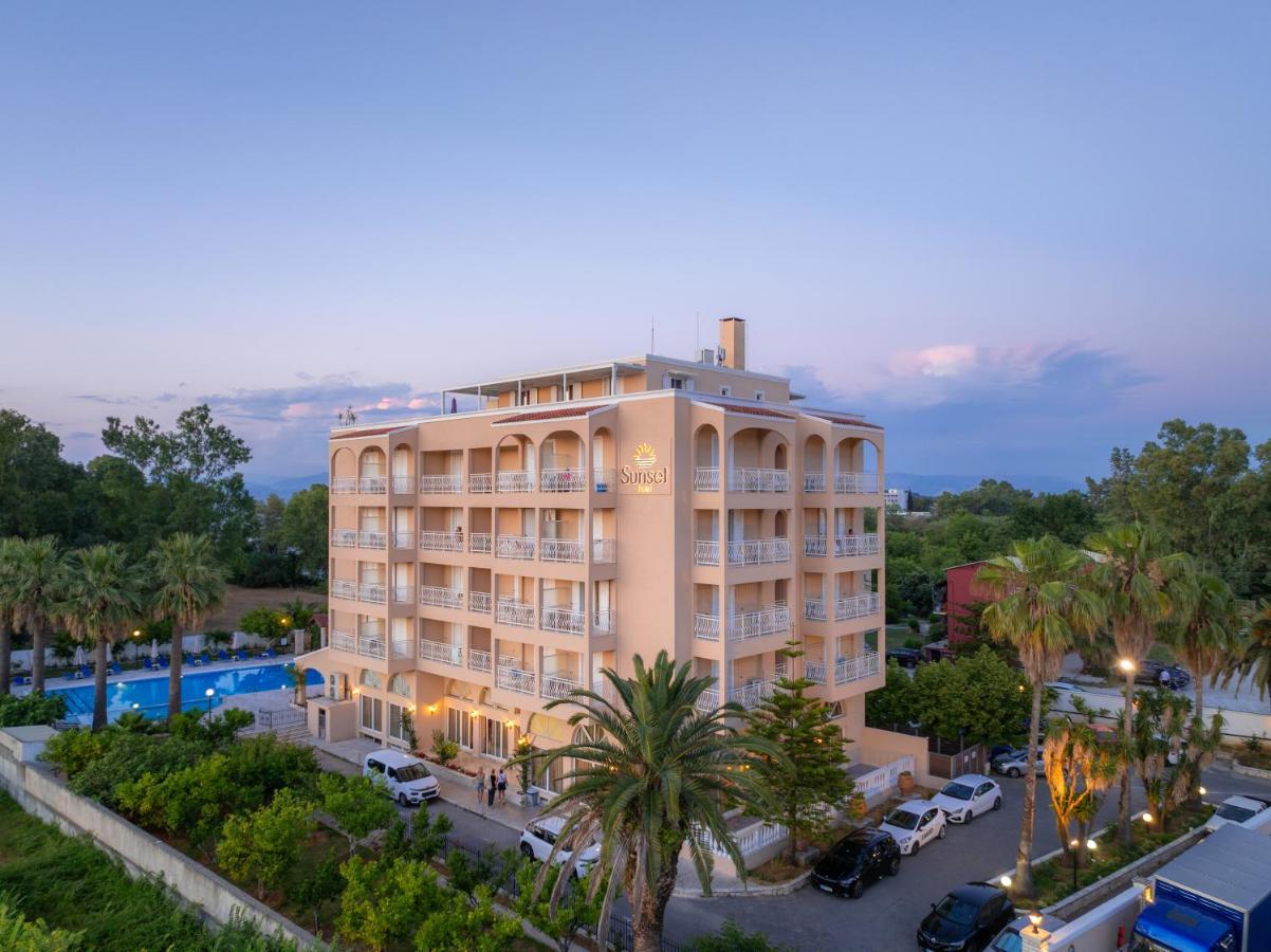 een groot gebouw met een parkeerplaats ervoor bij Sunset Hotel in Corfu-stad