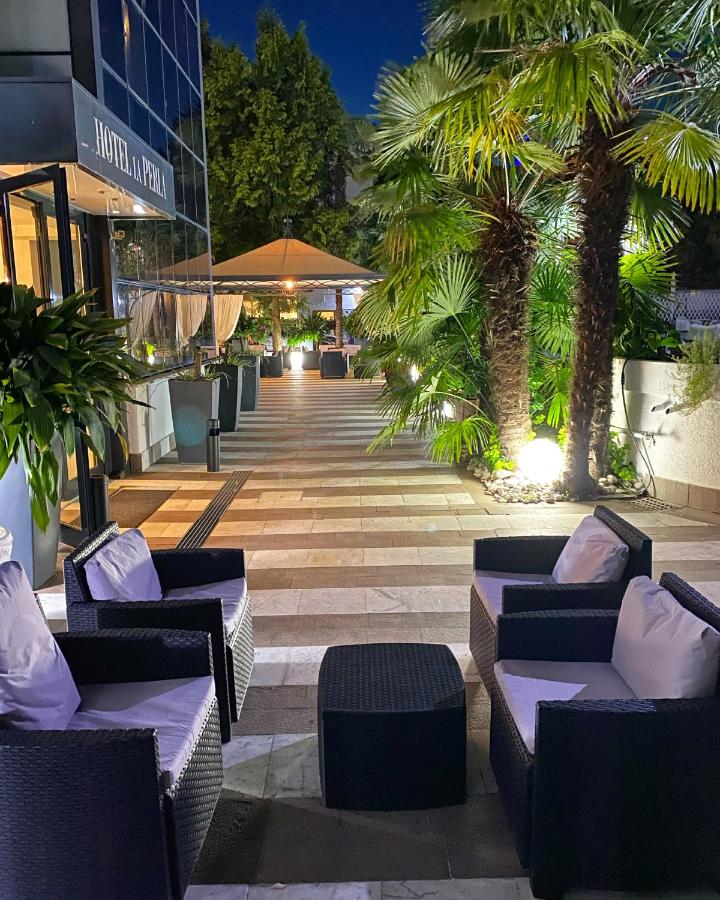 een patio met banken en palmbomen voor een gebouw bij Hotel La Perla in Riva del Garda +85 foto's