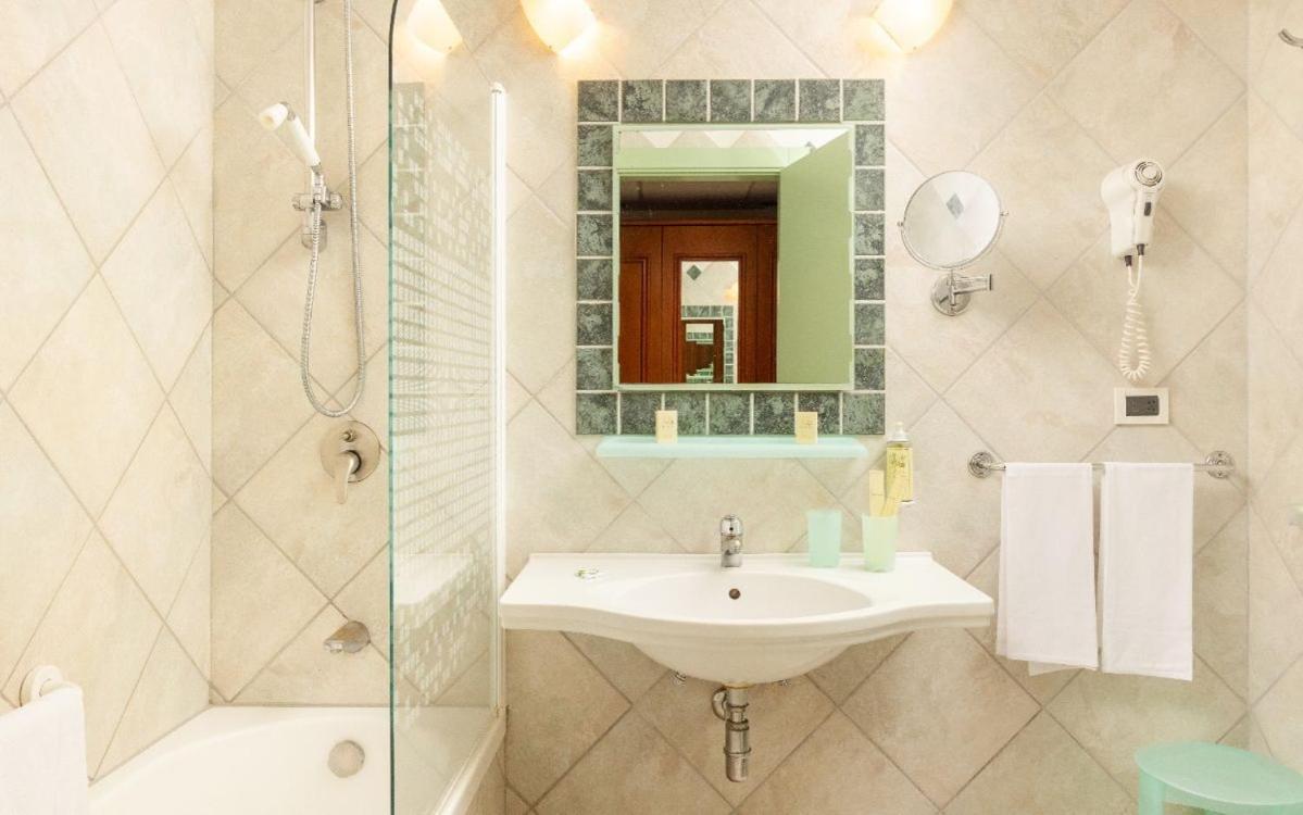 een badkamer met een wastafel, een douche en een spiegel bij Hotel Sierra Silvana in Selva di Fasano