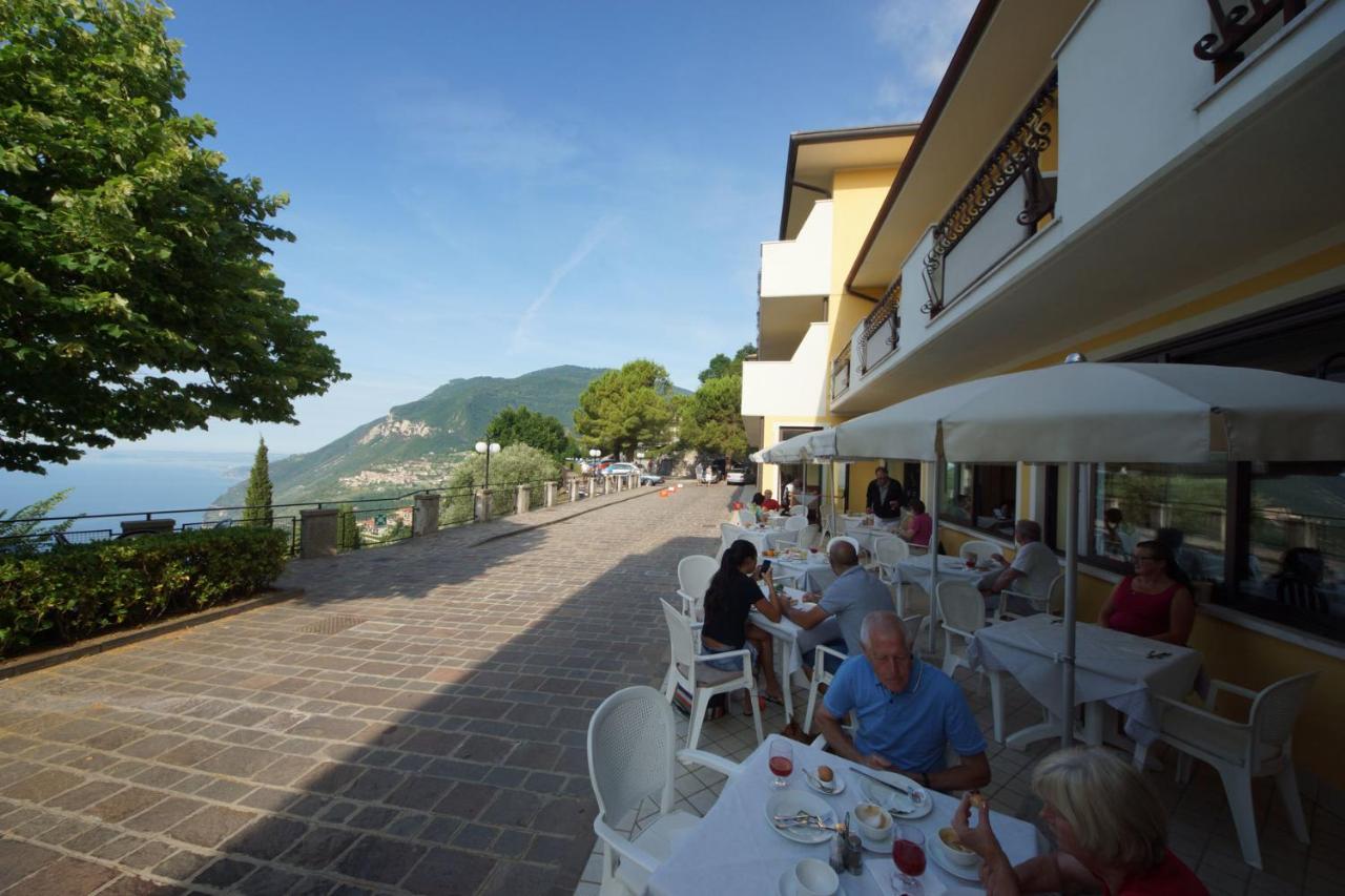 een groep mensen die aan tafels buiten een restaurant zitten bij Hotel Residence La Rotonda in Tignale