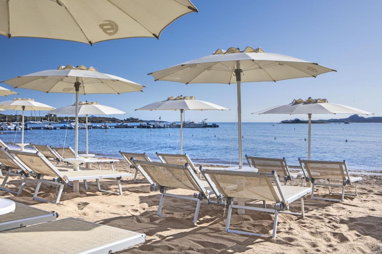 een groep stoelen en parasols op een strand bij Blu Hotel Laconia Village in Cannigione