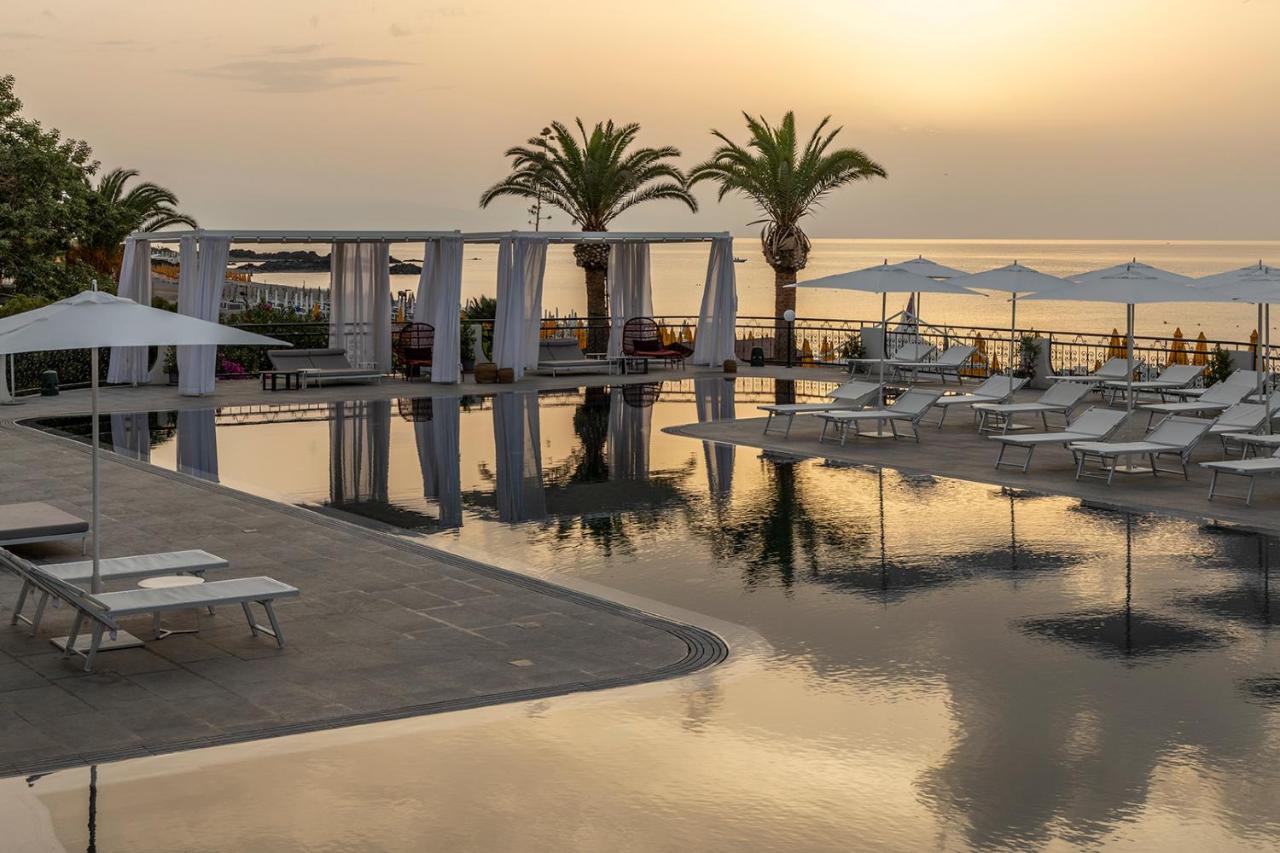 een zwembad met ligstoelen en parasols in een resort bij Delta Hotels by Marriott Giardini Naxos in Giardini Naxos
