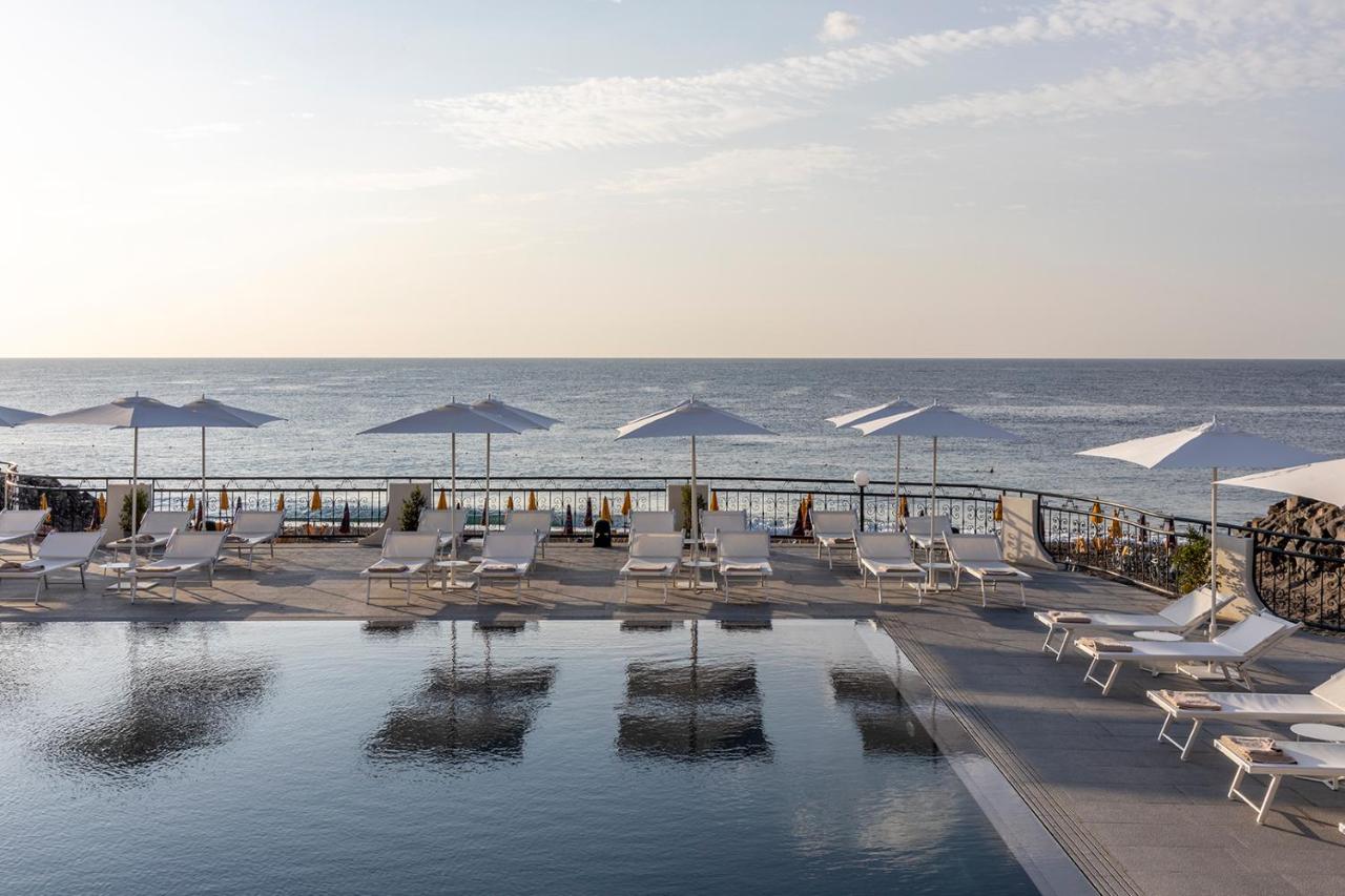 een zwembad met ligstoelen en parasols aan de oceaan bij Delta Hotels by Marriott Giardini Naxos in Giardini Naxos