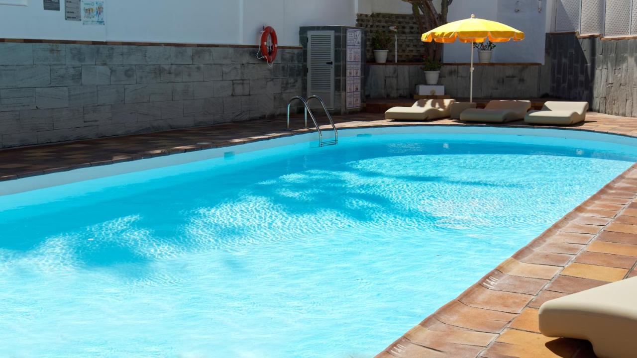 een groot blauw zwembad met stoelen en een parasol bij Jacarandas Beach in Playa del Inglés