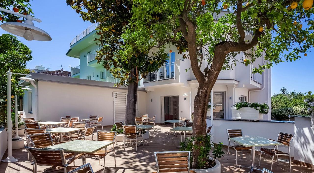 een terras met tafels en stoelen en een boom bij Hotel Angelina in Sant'Agnello