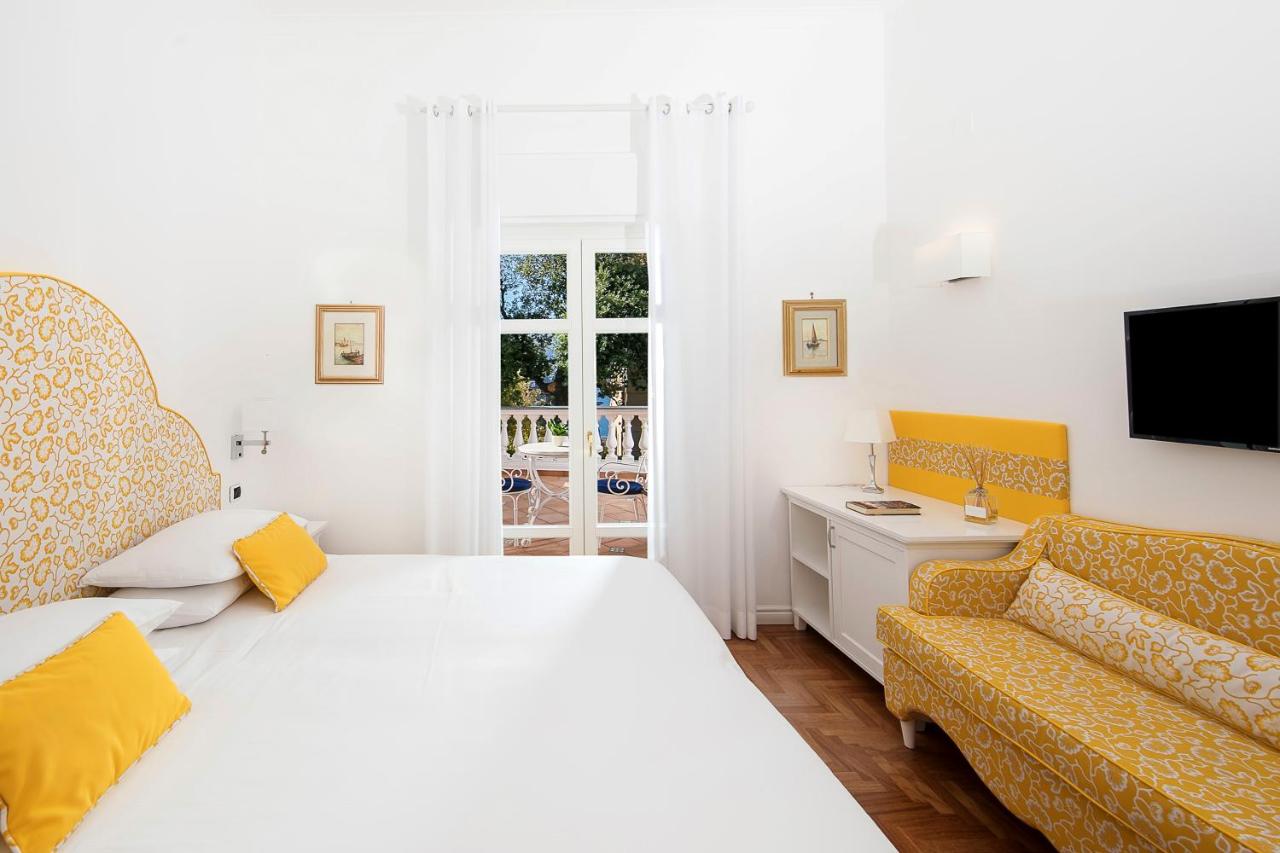 een slaapkamer met een wit bed en een bank bij Hotel Villa Garden in Sant'Agnello