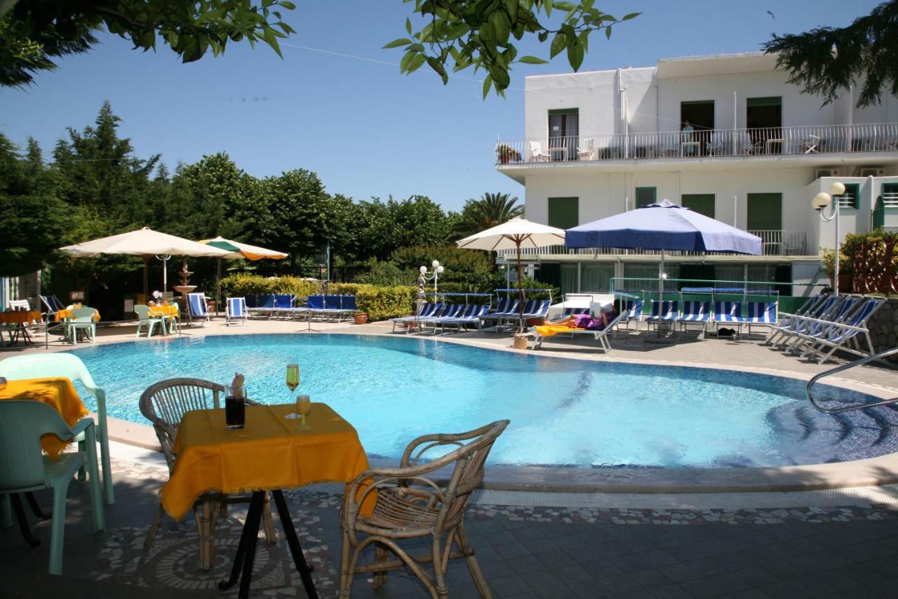 een zwembad met een tafel en stoelen en een gebouw bij Hotel Carmencita in Anacapri