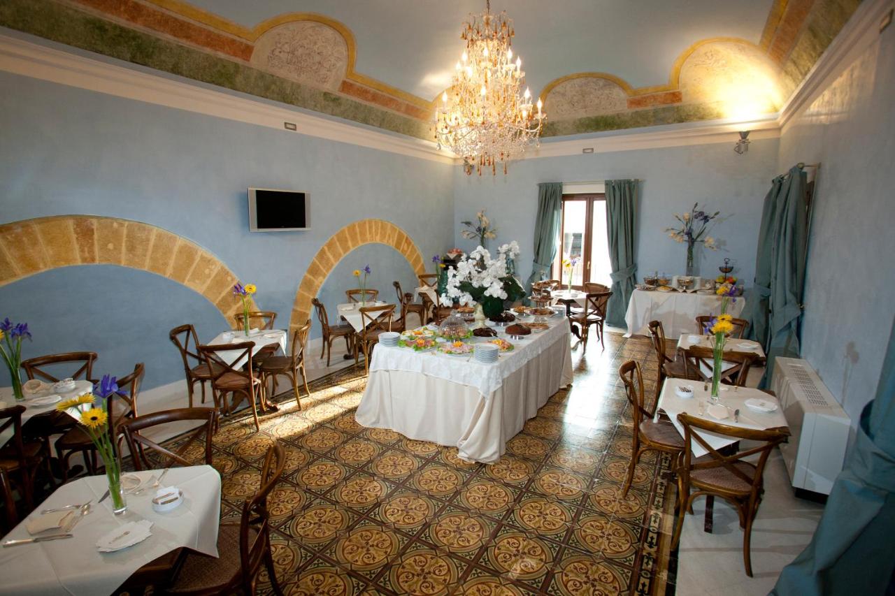 een eetkamer met tafels en stoelen en een kroonluchter bij Hotel Carmine in Marsala