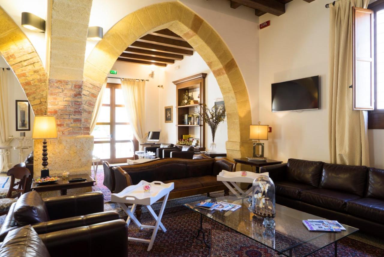een woonkamer met leren meubels en een boogdoorgang bij Hotel Carmine in Marsala
