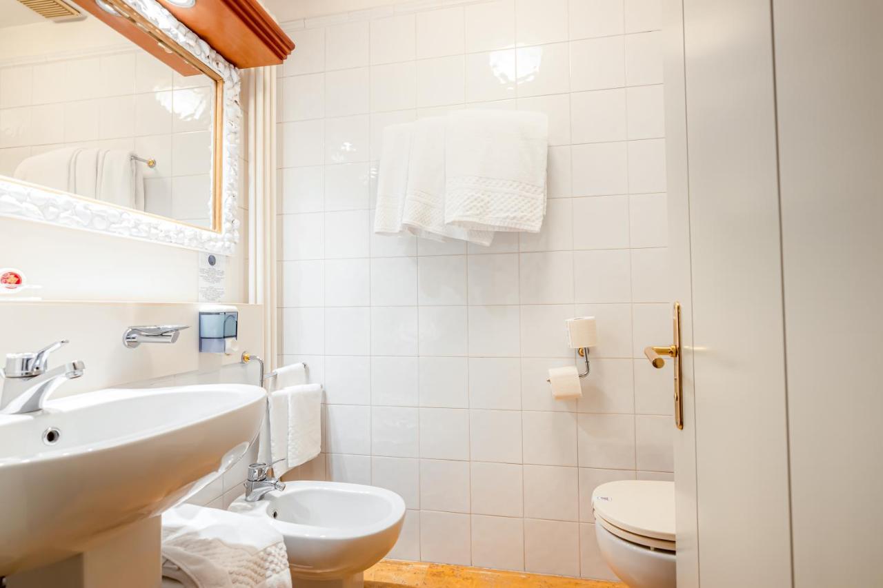 een witte badkamer met een wastafel en een toilet bij Hotel Della Porta in Santarcangelo di Romagna
