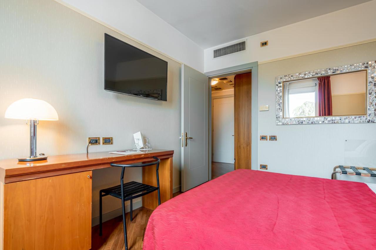 een slaapkamer met een bed en een bureau met een televisie bij Hotel Della Porta in Santarcangelo di Romagna