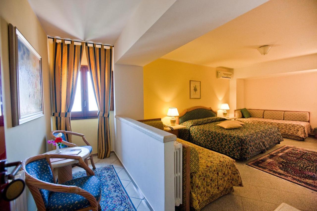 een hotelkamer met twee bedden en een stoel bij Hotel Elimo in Erice