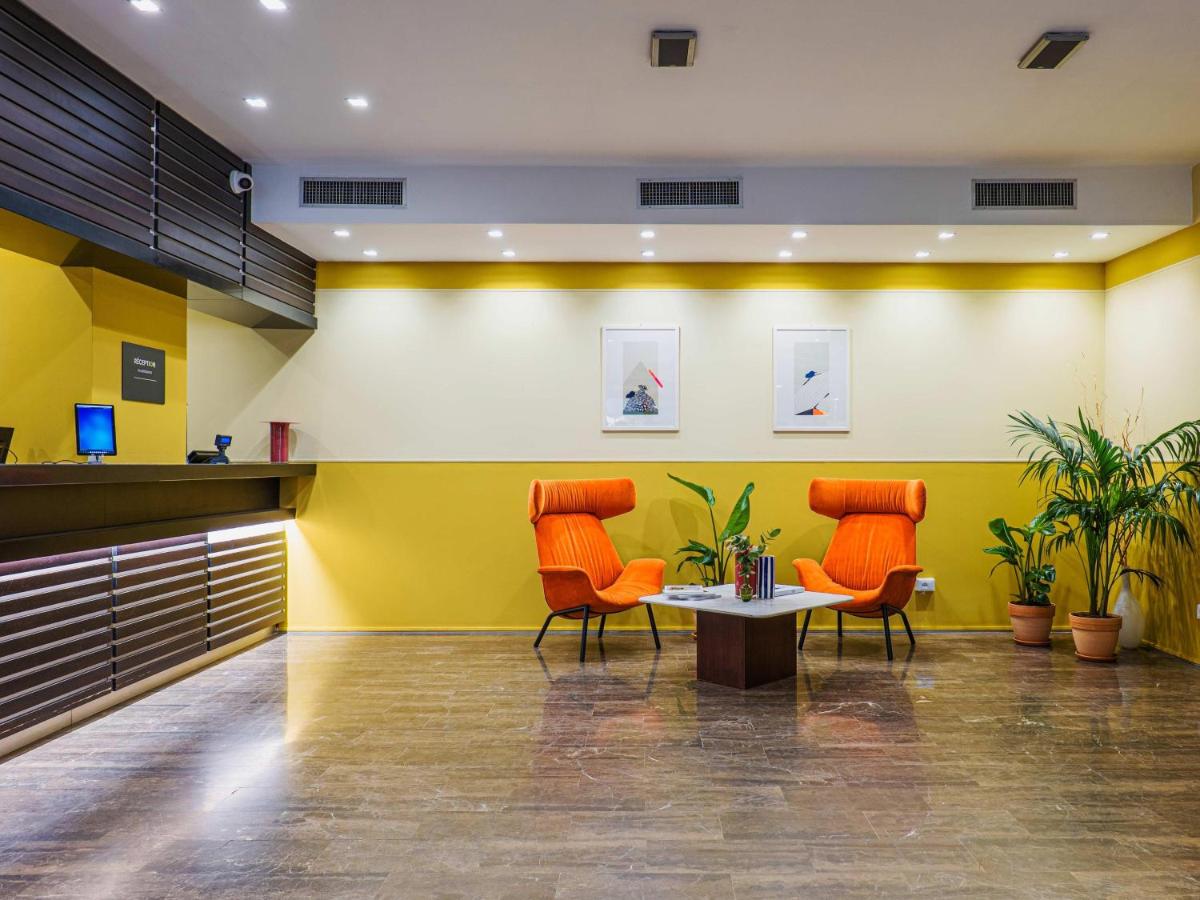 twee oranje stoelen en een tafel in een lobby bij B&B HOTEL Fabriano Janus in Fabriano