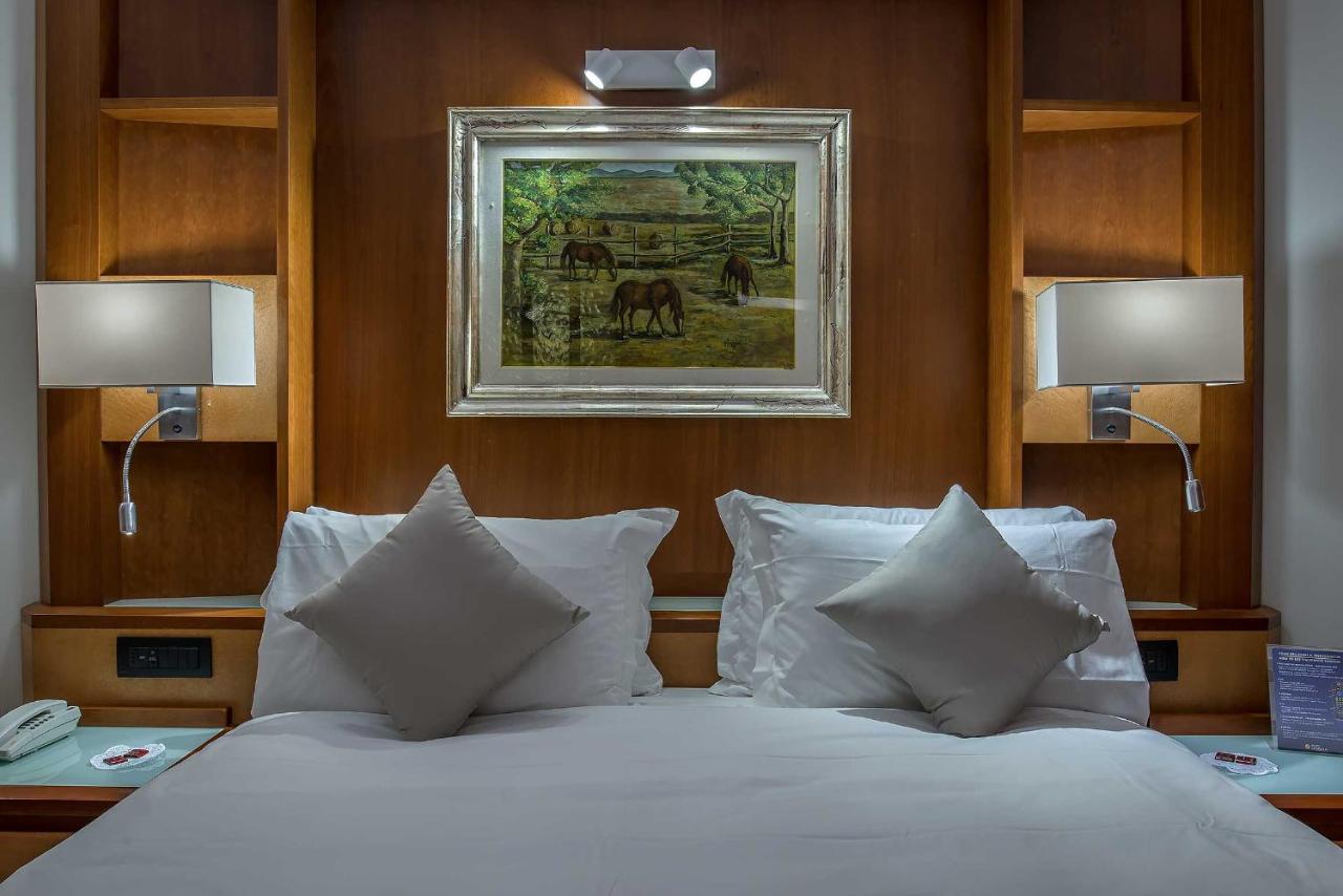 een slaapkamer met een bed met witte lakens en kussens bij Hotel La Giocca in Rome