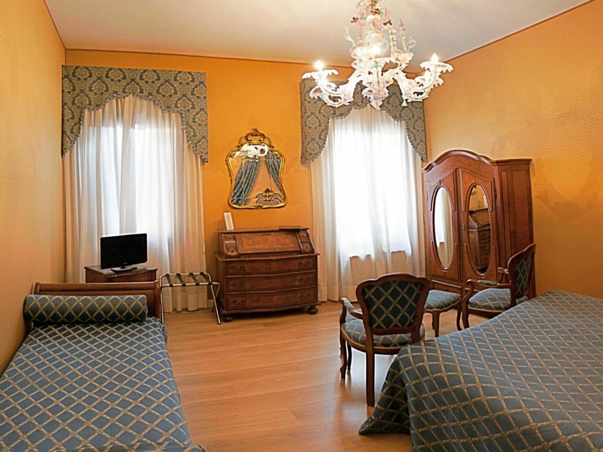 een slaapkamer met een bed, een bureau en een kroonluchter bij Hotel Locanda Canal in Venetië