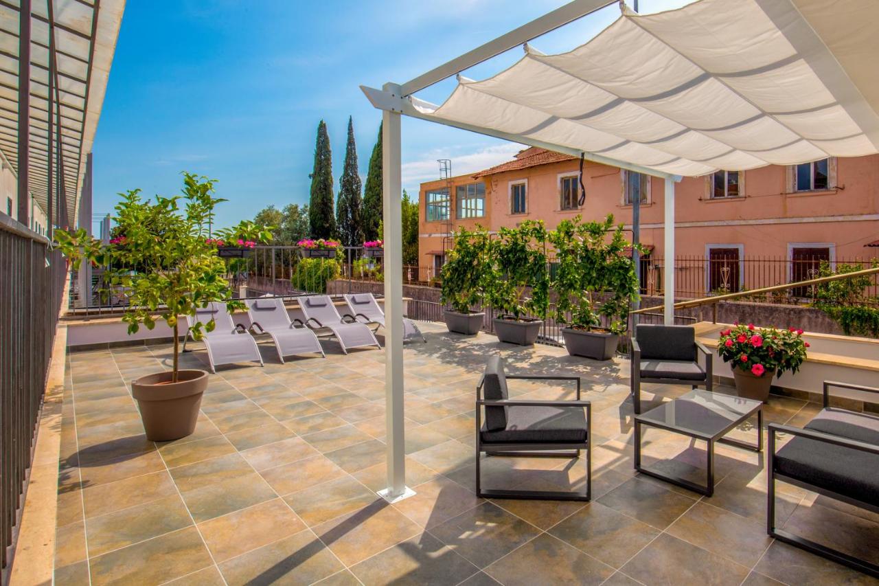 een terras met stoelen en een witte parasol bij Urban Garden Hotel in Rome