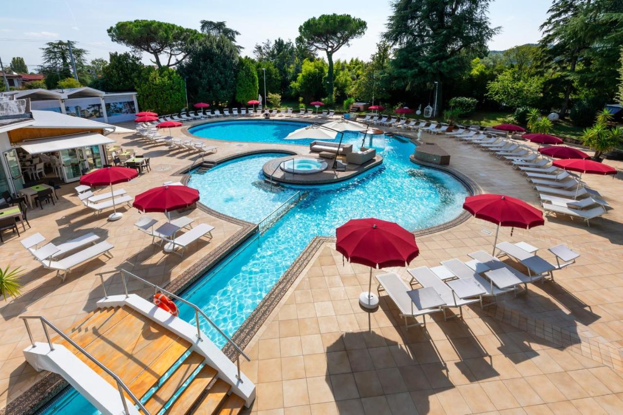 een afbeelding van een zwembad met rode parasols en ligstoelen bij Hotel Mioni Royal San in Montegrotto Terme
