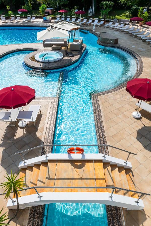 een bovenaanzicht van een zwembad met rode parasols bij Hotel Mioni Royal San in Montegrotto Terme