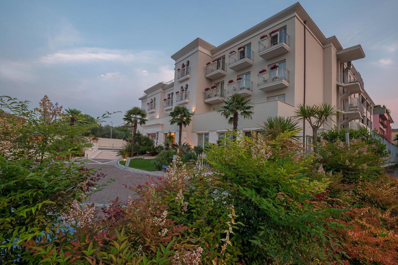 een groot gebouw met bomen ervoor bij Hotel Nazionale in Desenzano del Garda