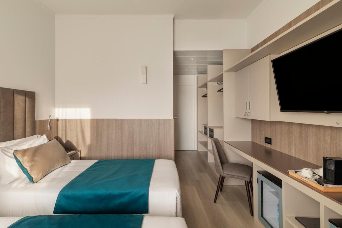 een hotelkamer met een bed en een bureau met een televisie bij Living Hotel Milano in Cornaredo