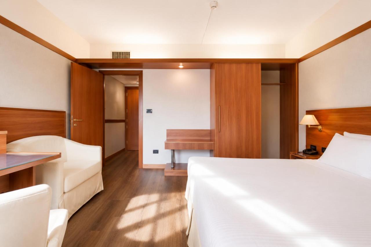 een slaapkamer met een bed, een tafel en een bankje bij SHG Hotel Bologna in Zola Predosa