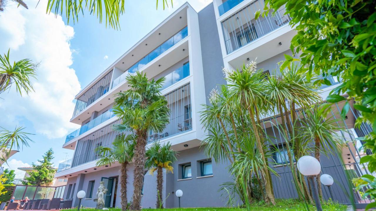 een appartementencomplex met palmbomen ervoor bij Hotel Bella Peschiera in Peschiera del Garda