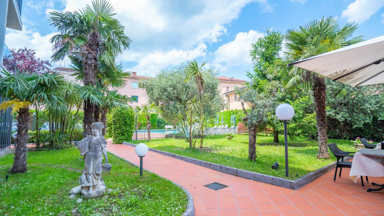 een binnenplaats met een standbeeld en palmbomen bij Hotel Bella Peschiera in Peschiera del Garda