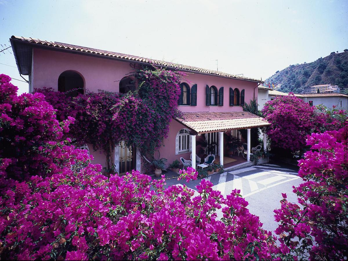 een huis met paarse bloemen ervoor bij Hotel Lido Mediterranee in Taormina