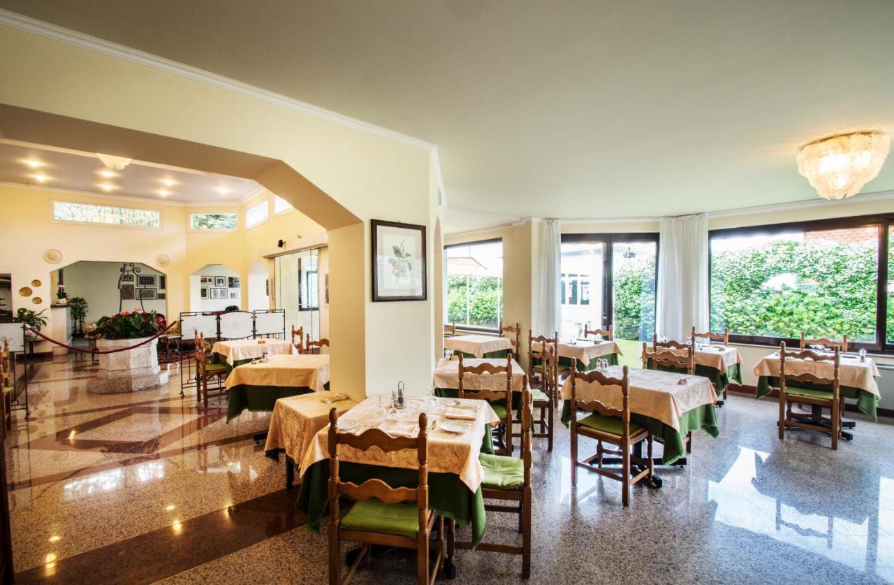 een restaurant met tafels en stoelen en grote ramen bij Hotel Lido La Perla Nera in Stresa